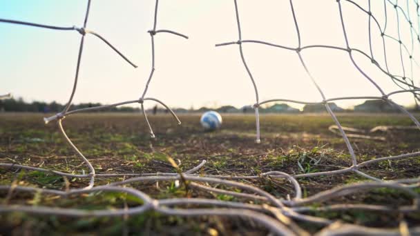 Close-up of a torn soccer net. Soccer ball through the net. Old gate soccer field. Street sport. Child Game. The sun shines through the grid. The crisis. Football. - Footage, Video