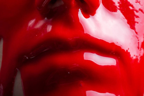 Tiro de uma cara de fêmeas com a pintura vermelha brilhante que se estende
 - Foto, Imagem