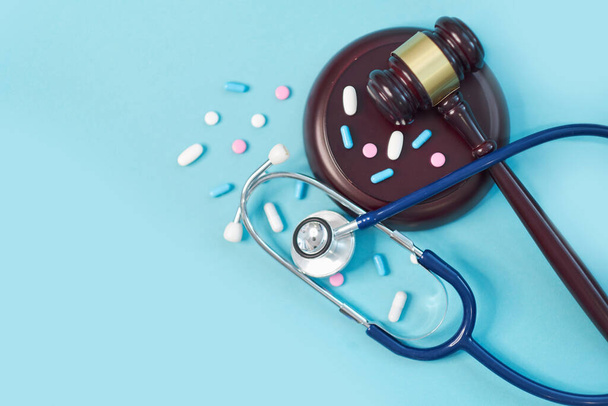 martelletto marrone e uno stetoscopio medico su sfondo blu. foto simbolo per errore e errore medico
. - Foto, immagini