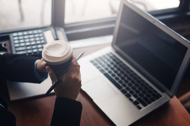 Businesswomen drink hot coffee between working. laptop, calculator and paper on the table. - Foto, Bild