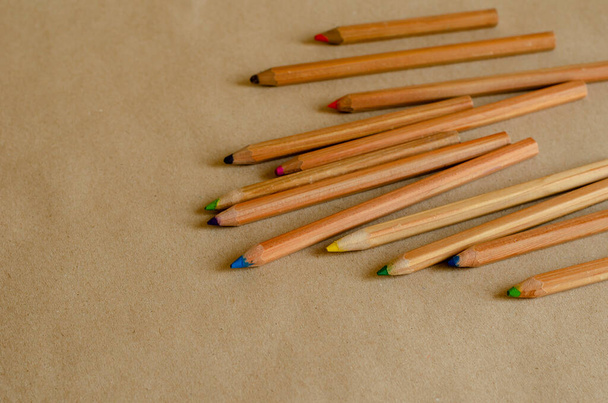 Кольорові олівці на бежевому фоні. Набір дерев'яних використовуваних олівців випадковим чином на столі. Зйомки на рівні очей. Вибірковий фокус
. - Фото, зображення