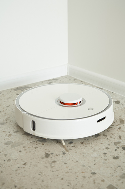 μοντέρνα ρομποτική ηλεκτρική σκούπα πλυσίματος πλακιδίων δαπέδου κοντά σε λευκούς τοίχους  - Φωτογραφία, εικόνα