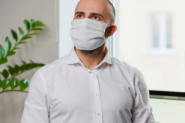 Мужчина в защитной маске от коронавируса. Менеджер в хирургической маске против 2019-nCoV. Врач в его кабинете. Карантин коронавируса
. - Фото, изображение