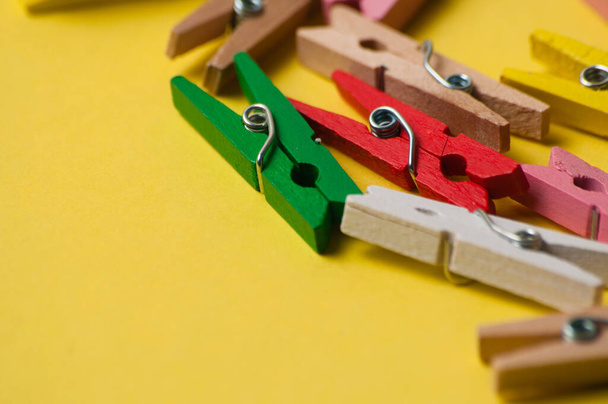 Multicolored decorative wooden clothespins on yellow ocher background, macro closeup, copy space - Photo, Image