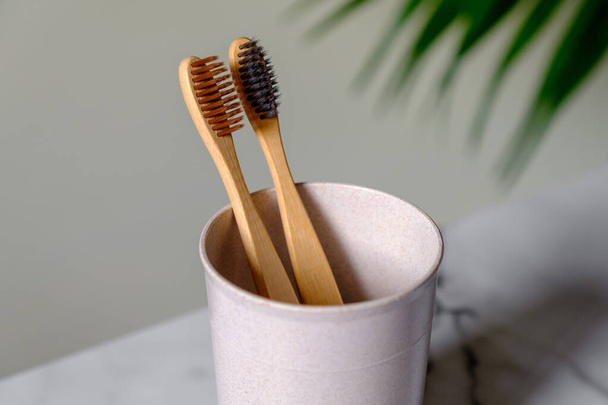Cup with organic bamboo toothbrushes on table, close up view. Dental care concept. - Фото, изображение