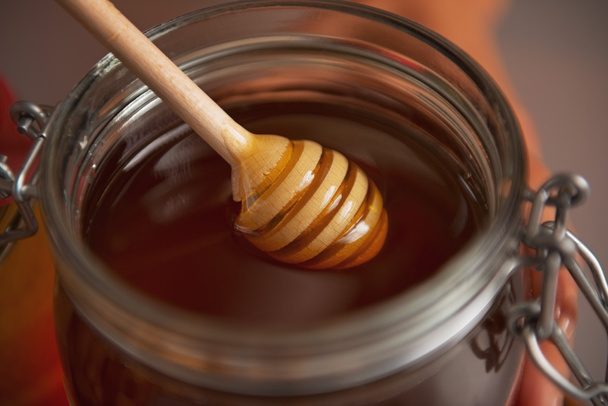 Closeup on honey dipper in honey jar - 写真・画像