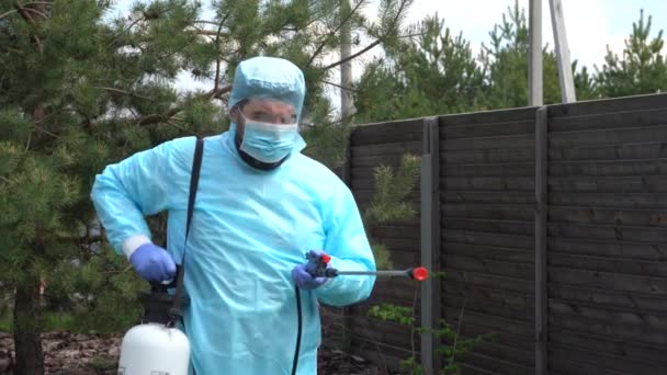 保護シェルの人は、プライベートコテージでCovid-19に対する予防措置として消毒剤をスプレーします。伝染病対策。ウイルスに対する防腐洗浄。農薬を散布する松。カメラにスプリンクル. - 映像、動画