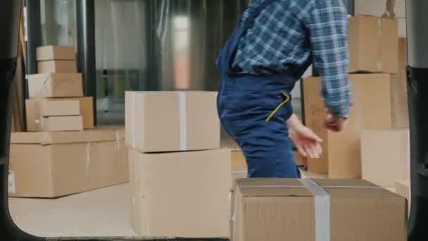 Wholesale warehouse worker loads cardboard boxes into the trunk of a van - Felvétel, videó