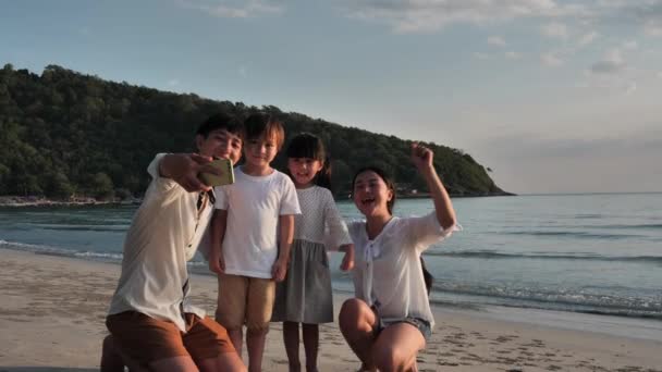 Happy Asian Family On Summer Vacation Father takes family photos with smartphone on the beach. Relax Holiday and Travel concept. Slow motion - Footage, Video