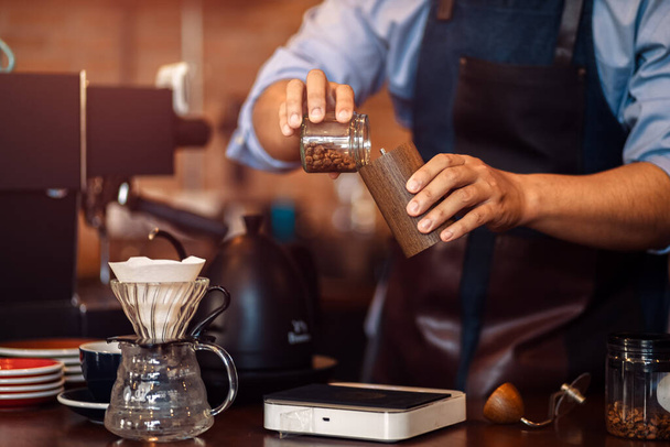 the barista hands on manual grinder coffee for grinding coffee beans at cafe. - 写真・画像