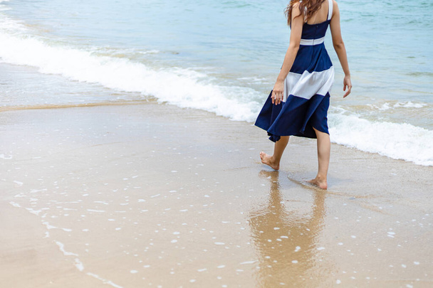 Woman barefoot walking on summer along wave of sea water and sand on the beach.  - 写真・画像