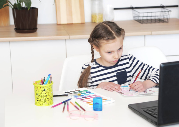 Jolie fille avec ordinateur portable apprend la peinture à l'école à la maison éducation
.   - Photo, image