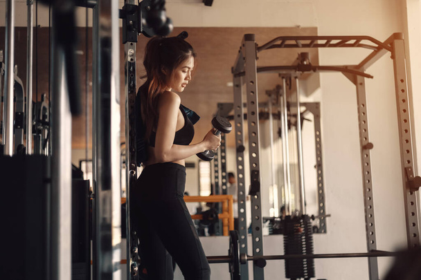 Fitness girl lifting dumbbell at fitness, gym. - Foto, Imagen