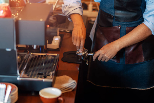 Barista holding portafilter and coffee tamper making  coffee at cafe.  - 写真・画像