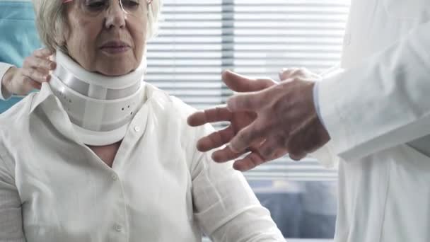 Doctor examining an injured senior woman with cervical collar - Materiaali, video