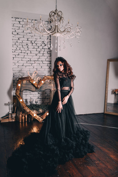 uma menina bonita em um vestido preto com cabelo marrom posa em um estúdio de fotos
 - Foto, Imagem