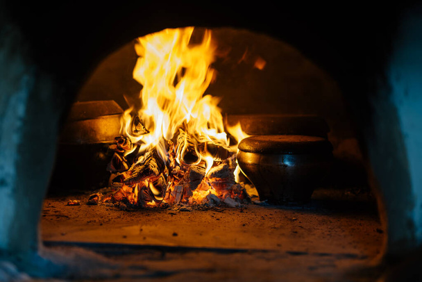 Βρύσες και τηγάνια στο φούρνο πάνω από μια φυσική φωτιά για το μαγείρεμα. φωτιά καμίνου - Φωτογραφία, εικόνα