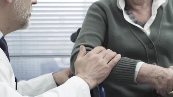 Doctor consolando a un paciente mayor en una silla de ruedas
 - Imágenes, Vídeo