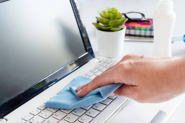 Woman hand disinfecting computer keyboard with antibacterial cloth. Hygiene concept and protection against bacteria. - Фото, изображение