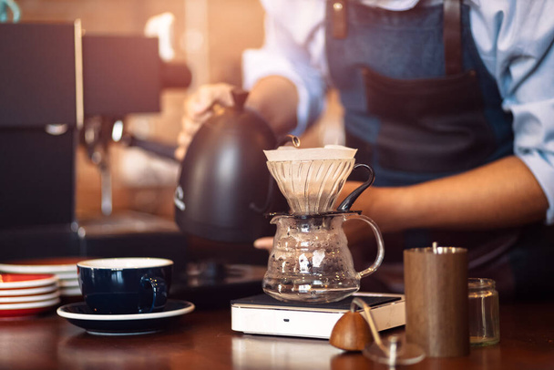barista pouring boiling water from kettle to drip coffee maker. - Foto, Bild