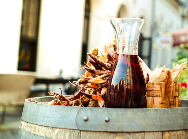 a carafe of red wine next to hot peppers on a barrel - Photo, Image