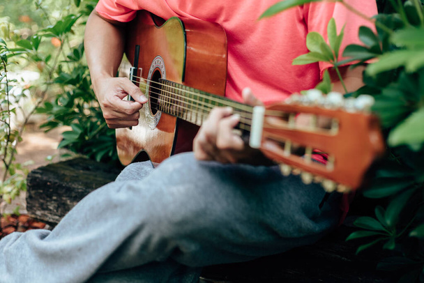 manos del hombre tocando la guitarra acústica divertirse al aire libre, de cerca
. - Foto, Imagen