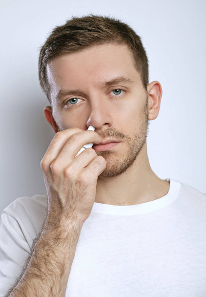 Guy druipt neusdruppels in neus, portret, close up - Foto, afbeelding