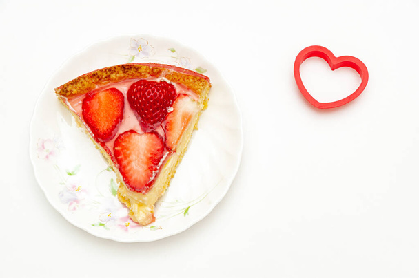 Delicious slice homemade strawberry tart with heart-shaped object on the side. Isolated on white background. Copy space. Top view. Close-up. Horizontal shot. - Photo, Image