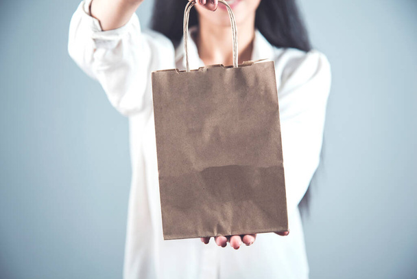 happy woman hand shopping bag on gray background - Zdjęcie, obraz