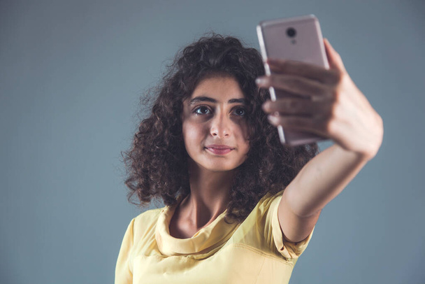 νεαρή γυναίκα τηλέφωνο στο χέρι selfie σε γκρι φόντο - Φωτογραφία, εικόνα