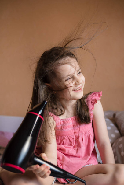 5 years old girl blow dry her hair in her room - Foto, Bild