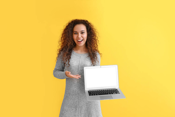 Beautiful young African-American woman with laptop on color background - Foto, immagini