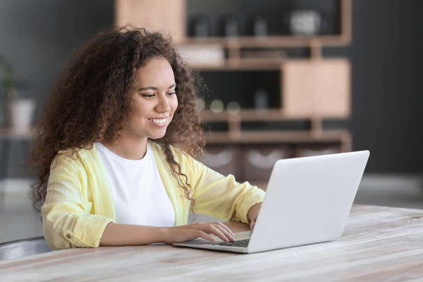 Young African-American woman with laptop at table - Foto, imagen