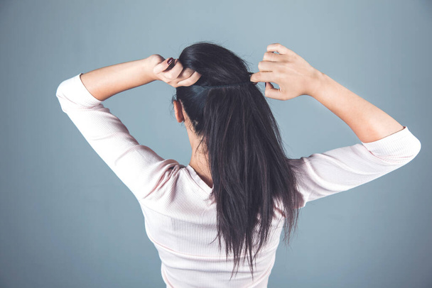 woman tie the hair on the gray background - Foto, imagen