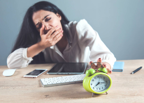 tired woman hand clock on the desk - Фото, изображение