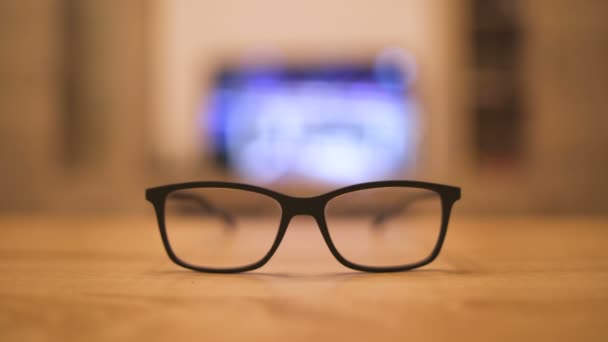 Pair of black frame glasses resting on table - Footage, Video