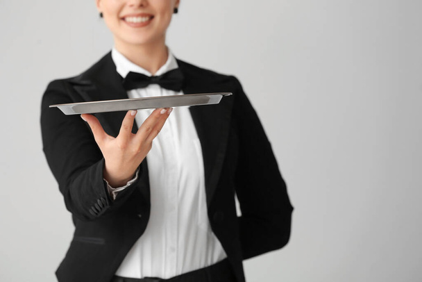 Female waiter with empty tray on grey background - Photo, Image