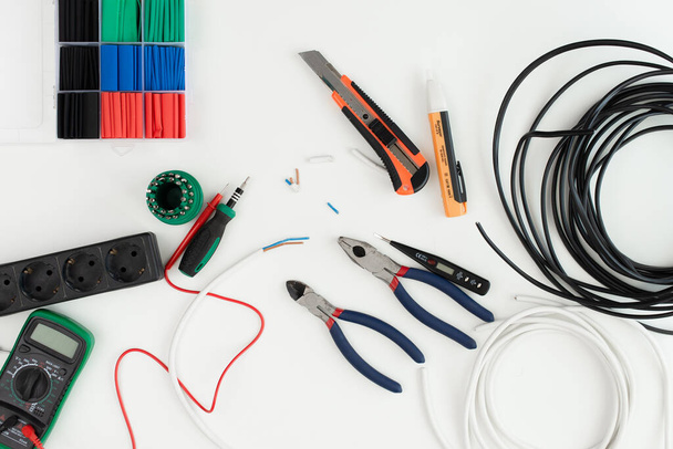bare wires. wire insulation. electrician's tools on a white background. an electrician working at a table. - Foto, afbeelding