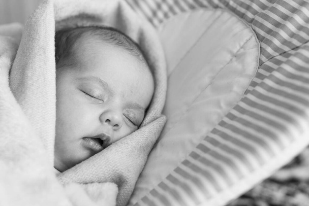 Schlafendes Neugeborenes eingewickelt in eine Decke auf dem Hängemattenstuhl. Konzept der süßen Träume - Foto, Bild