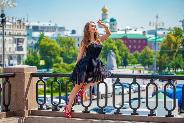 Portrait in full growth, Young beautiful brunette woman in black dress posing outdoors in sunny weather - Foto, imagen