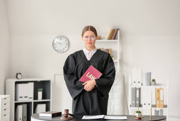 Жінка-суддя з юридичною книгою в офісі
 - Фото, зображення