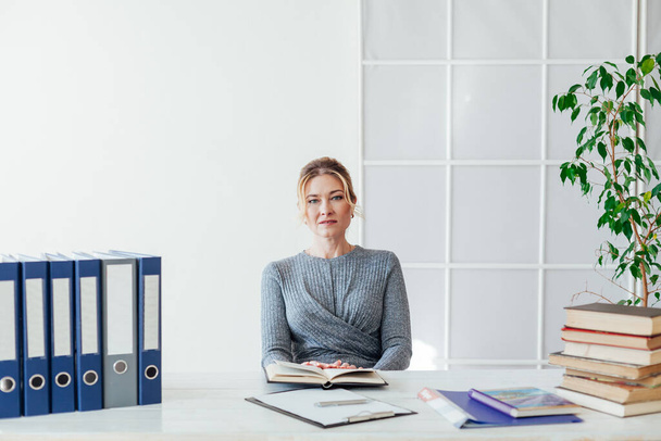 portret pięknej bizneswoman przy stole z książkami w pracy w biurze - Zdjęcie, obraz
