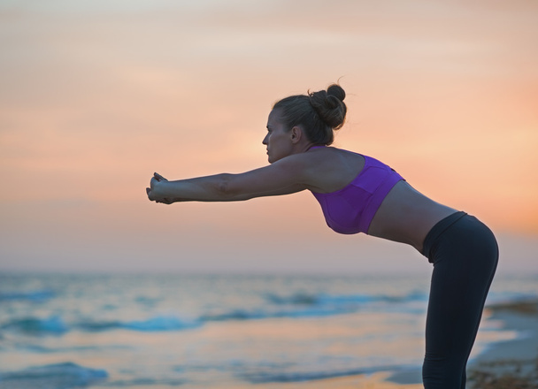 Fitness young woman stretching on beach in the evening - Fotoğraf, Görsel