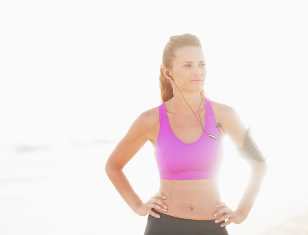 Portrait of fitness young woman in headphones outdoors in rays o - Photo, Image