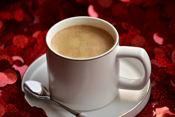 Tasse blanche avec café sur un fond de scintillements rouges. Vue rapprochée d'un café dans un verre à boire sur un fond rouge étincelant. Espresso sur fond rouge. Café du matin
 - Photo, image