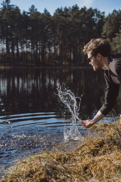 man on the lake, washes his hands, makes spray, rest in the woods on nature. - Fotografie, Obrázek