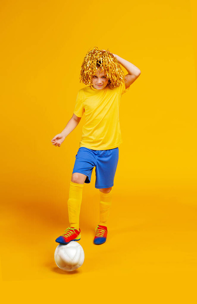 έφηβος αγόρι με μπάλα ποδοσφαίρου και pompons για τους οπαδούς στο κεφάλι του - Φωτογραφία, εικόνα