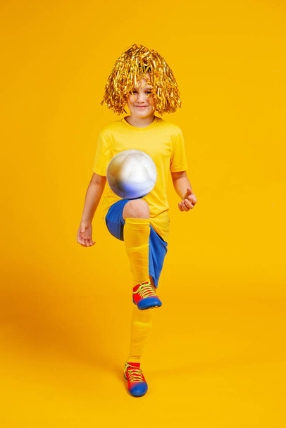 niño con una pelota de fútbol y pompones para los fans en la cabeza
 - Foto, imagen