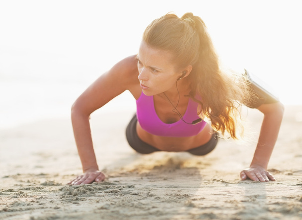 Fitness young woman doing push ups on beach - Zdjęcie, obraz