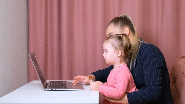 Working mom works from home office. Happy mother and daughter smiling. Successful woman and cute child using laptop. Freelancer workplace. Female business. It is not easy but she is up to the task - Photo, Image